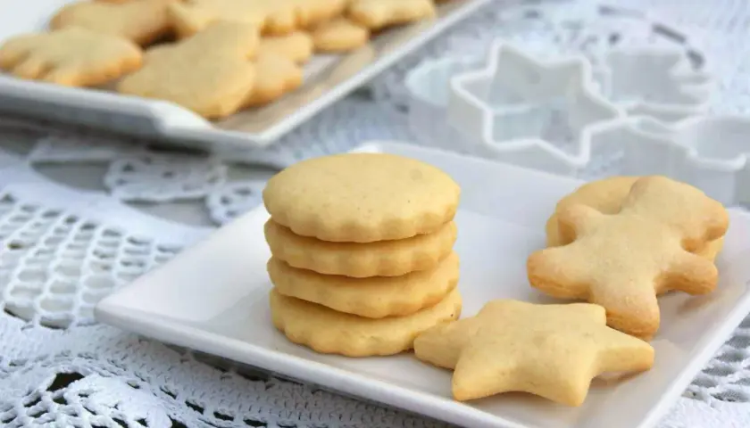 Deliciosas galletas caseras en forma de estrella y muñeco, apiladas en un plato blanco.