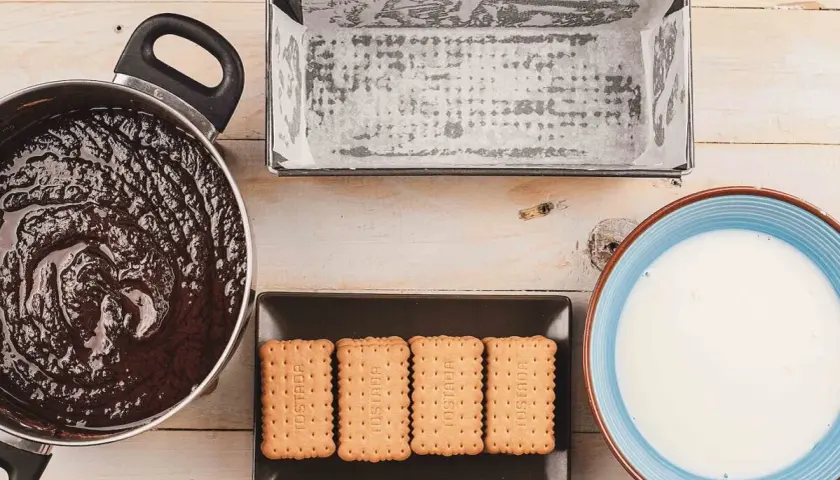 Preparando una deliciosa tarta de galletas y chocolate: chocolate derretido, galletas, molde y leche.