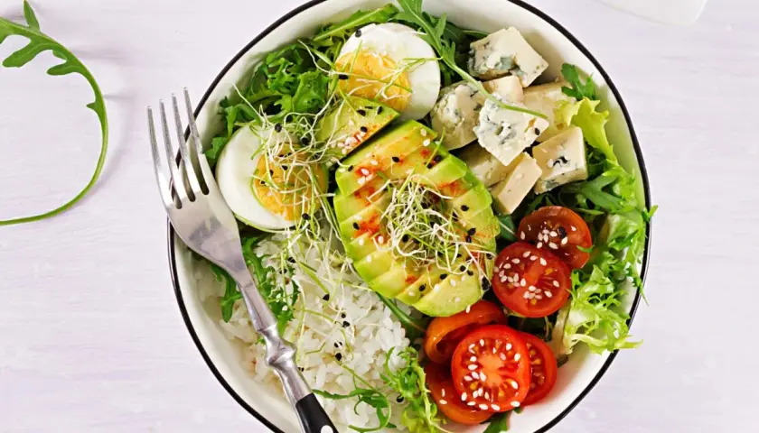Deliciosa ensalada de aguacate con huevo cocido, queso azul, tomates cherry, brotes y arroz blanco.