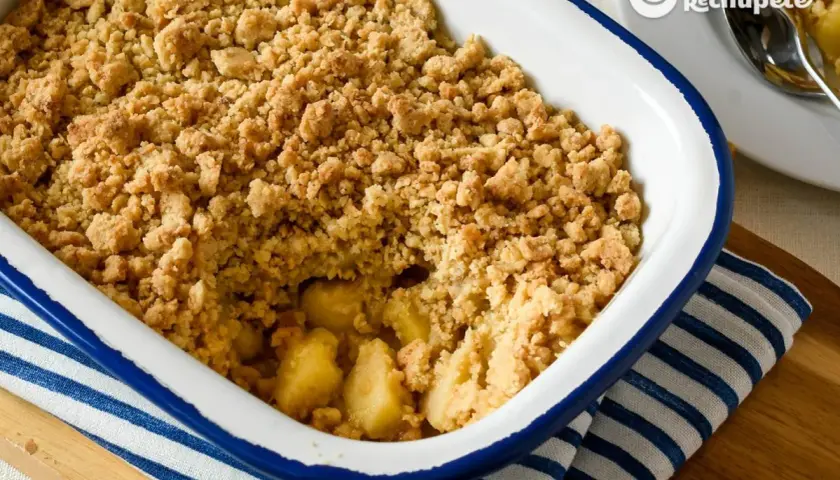 Un delicioso crumble de manzana recién horneado, con trozos dorados de manzana bajo una capa crujiente de migas.