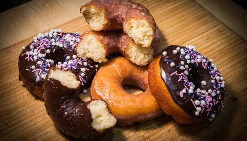 Deliciosos donuts caseros, algunos cubiertos de chocolate y chispas, otros glaseados, listos para disfrutar.