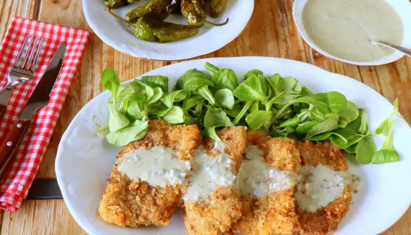 Escalopines al cabrales crujientes, servidos con ensalada verde y pimientos de Padrón.