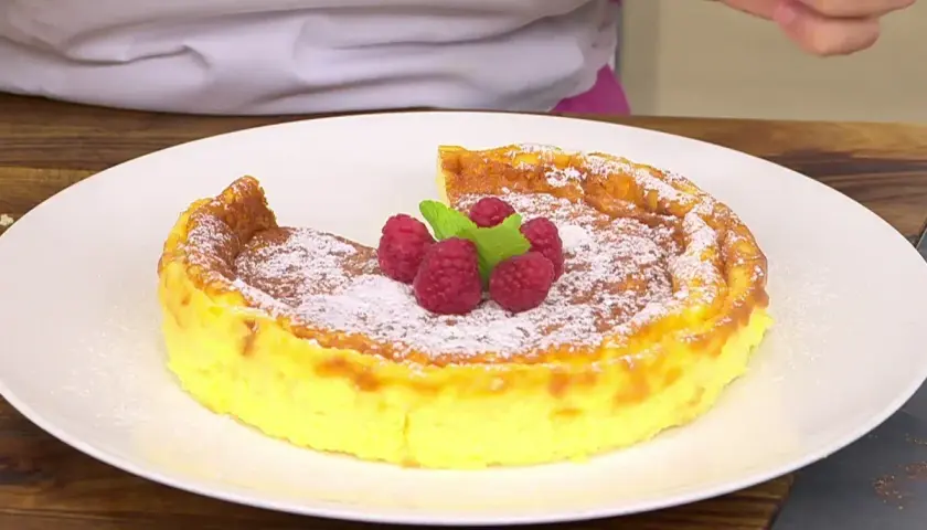 Tarta de queso Eva Arguiñano, dorada y espolvoreada con azúcar glas, coronada con frambuesas y menta. ¡Un postre irresistible!