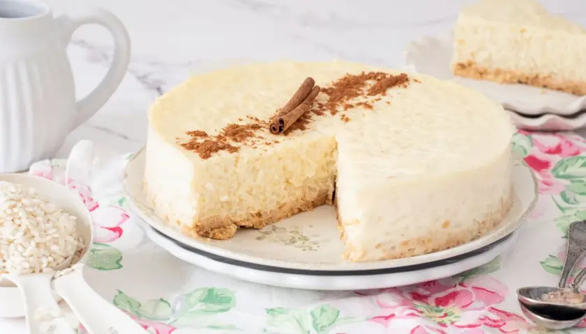 Deliciosa tarta de arroz cremosa, decorada con canela en rama y espolvoreada. Un trozo ya servido.