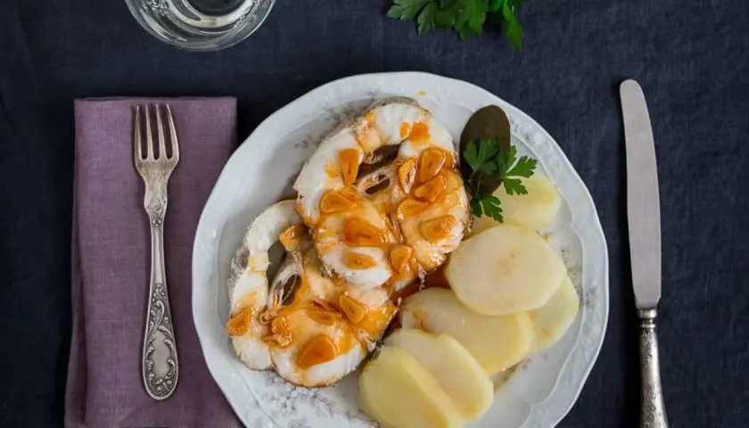 Merluza a la gallega con patatas cocidas, ajo dorado y perejil. Un plato tradicional listo para disfrutar.