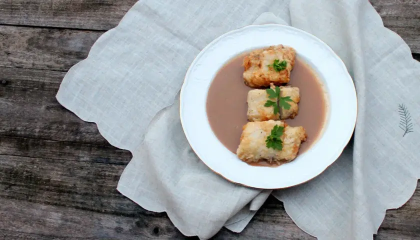 Tres trozos de bacalao rebozado en una salsa cremosa, decorados con perejil. Una de las muchas deliciosas recetas de bacalao.