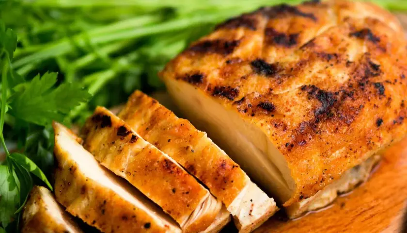 Pechuga de pollo a la parrilla, jugosa y dorada, lista para ser parte de tus recetas con pechuga de pollo. Acompañada de perejil fresco.
