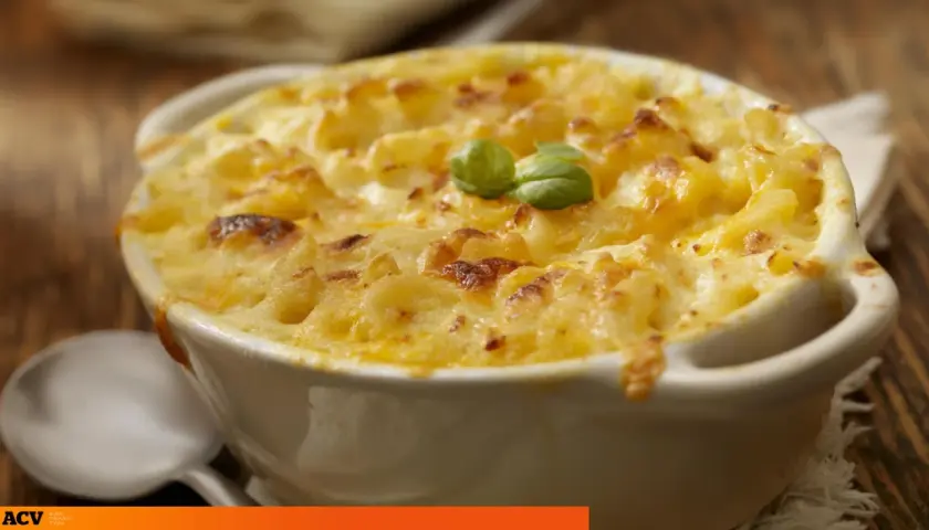 Un plato cremoso de macarrones con queso, gratinado y decorado con una hoja de albahaca.
