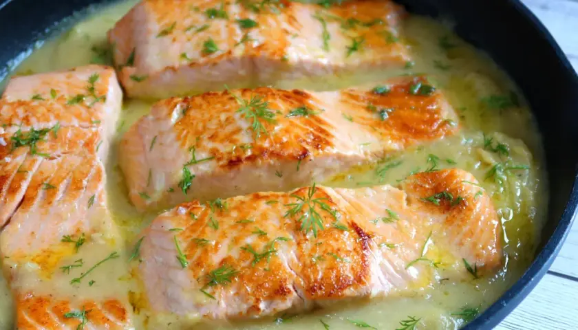 Filetes de salmón dorados en una cremosa salsa de eneldo, perfectos para tus recetas con salmón.