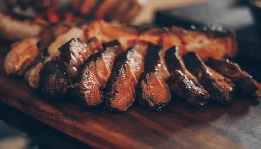 Filete de ternera jugoso y perfectamente cocinado, cortado en rodajas y servido en una tabla de madera.