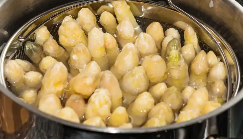 Espárragos blancos cocinándose en una olla.