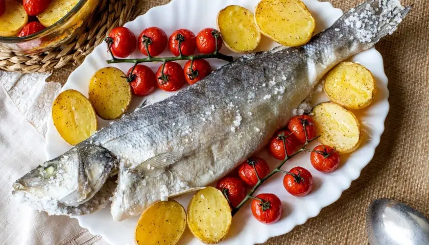 Lubina a la sal entera, horneada con patatas y tomates cherry. Un plato principal delicioso y saludable.