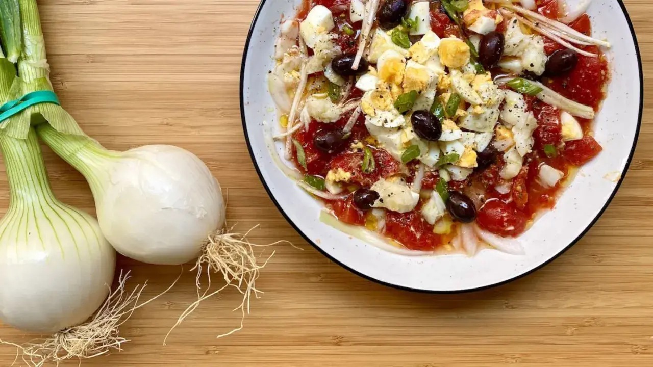 Deliciosa ensalada murciana con tomates, huevos duros, aceitunas negras y cebolla tierna, lista para disfrutar.