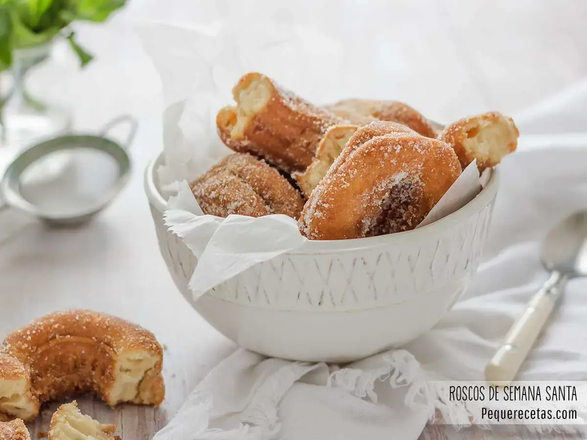 Roscos de Semana Santa espolvoreados con azúcar, servidos en un cuenco blanco.