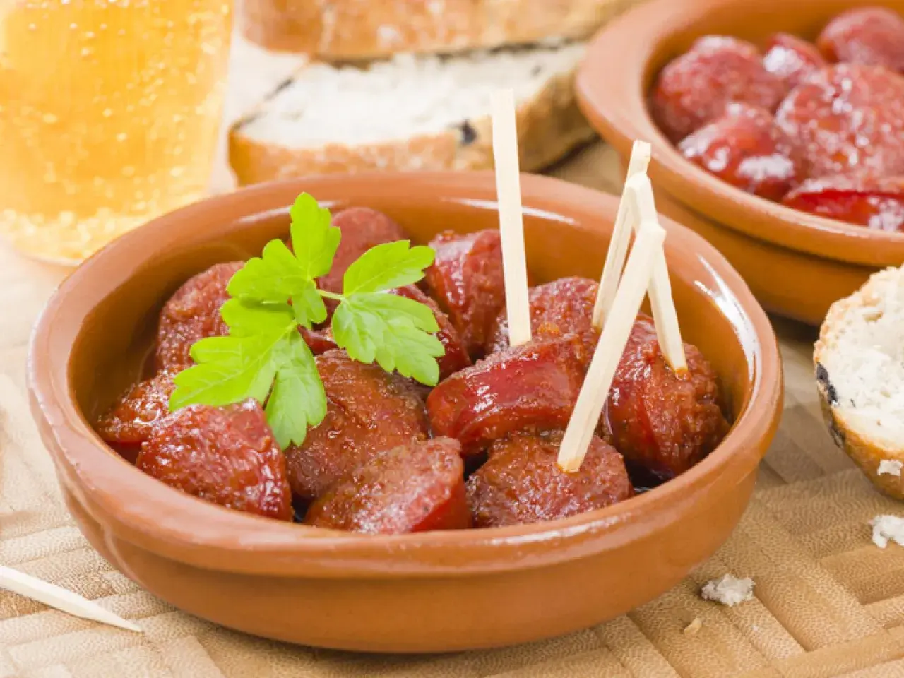 Delicioso chorizo a la sidra en cazuela de barro, adornado con perejil fresco. Acompañado de pan y una cerveza.