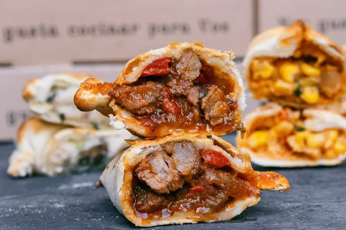 Empanada de carne jugosa y sabrosa, cortada por la mitad, revelando su relleno de carne y pimientos.