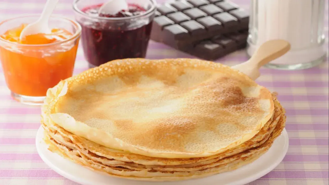 Una pila de crepes doradas, listas para disfrutar con mermelada de frutos rojos, albaricoque y chocolate. ¡Una deliciosa receta crepes!