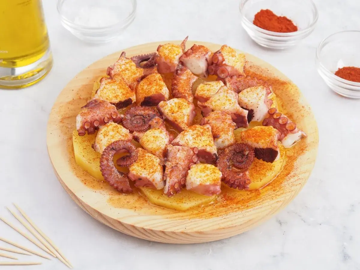 Pulpo a la gallega servido sobre patatas cocidas, espolvoreado con pimentón y aceite de oliva.