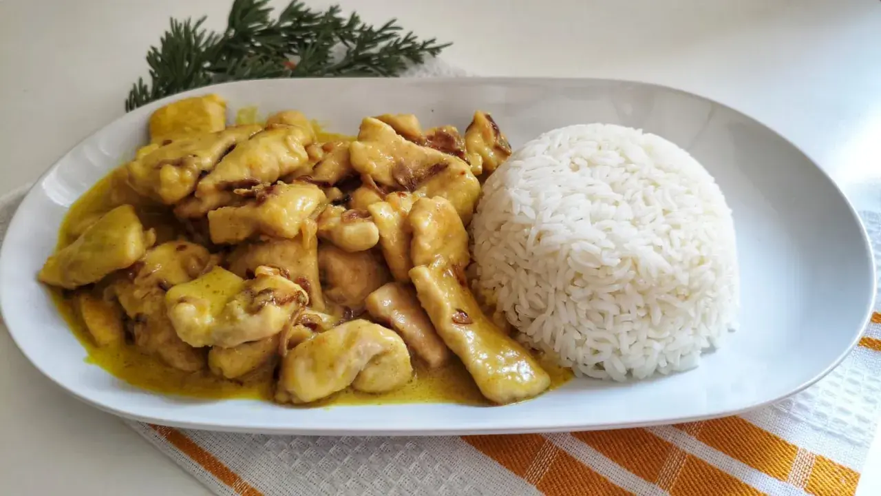 Sabroso pollo al curry cremoso servido con una porción generosa de arroz blanco.