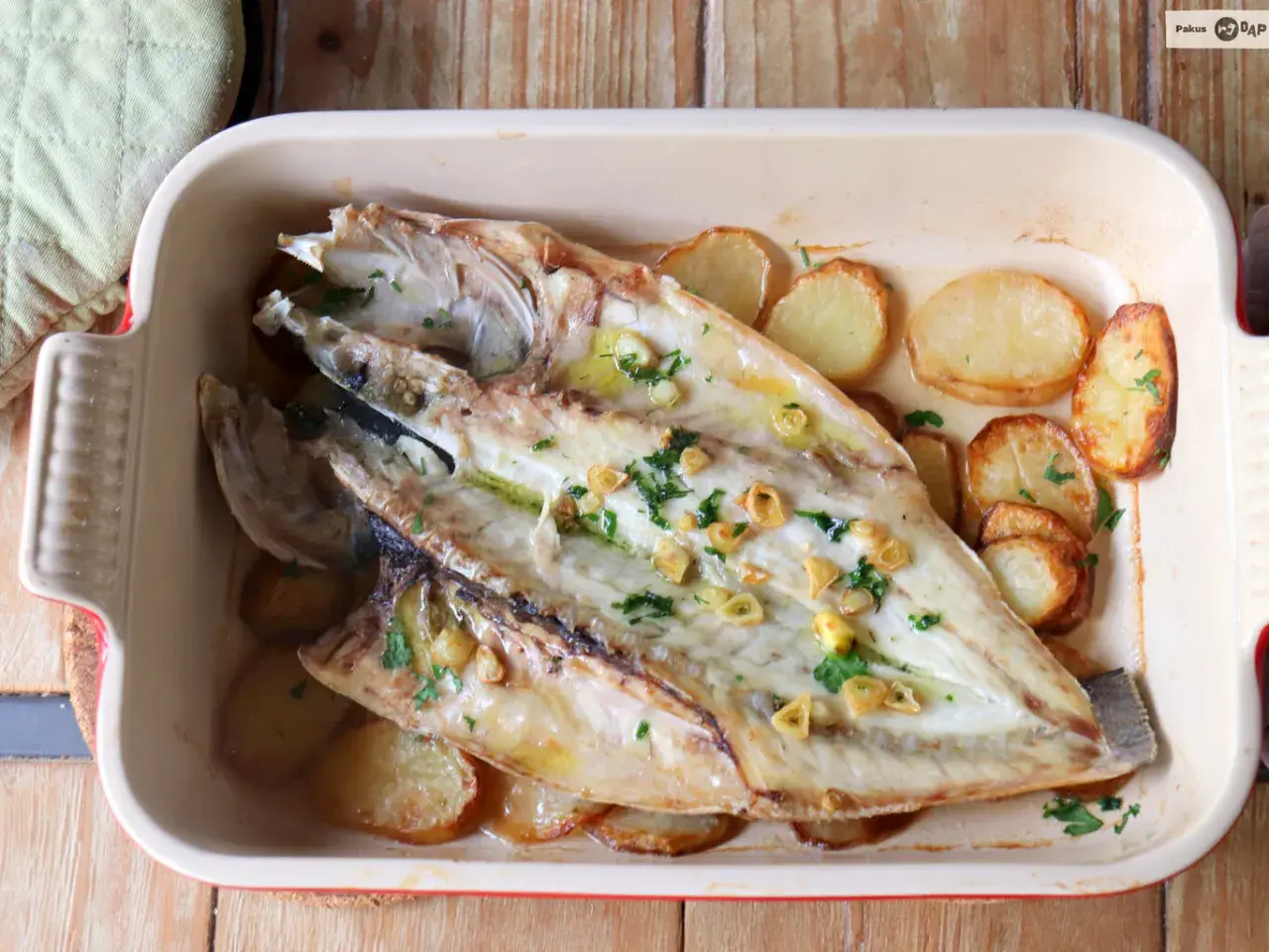 Lubina a la espalda horneada con patatas y ajo, lista para servir.