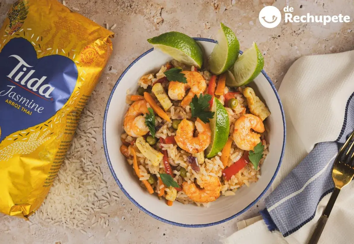 Delicioso arroz con langostinos, zanahoria, guisantes y pimiento rojo, decorado con lima y perejil. ¡Un plato para chuparse los dedos!
