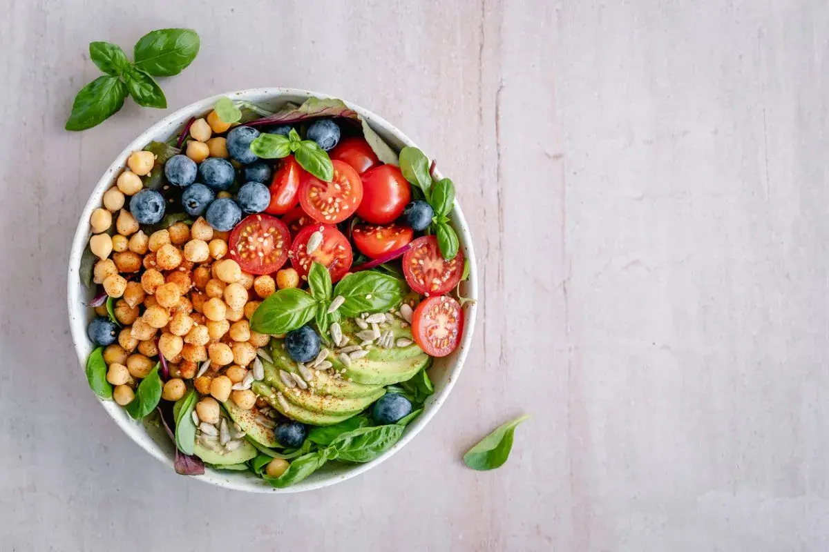 Deliciosa ensalada de legumbres con garbanzos, arándanos, tomates cherry, aguacate y semillas.
