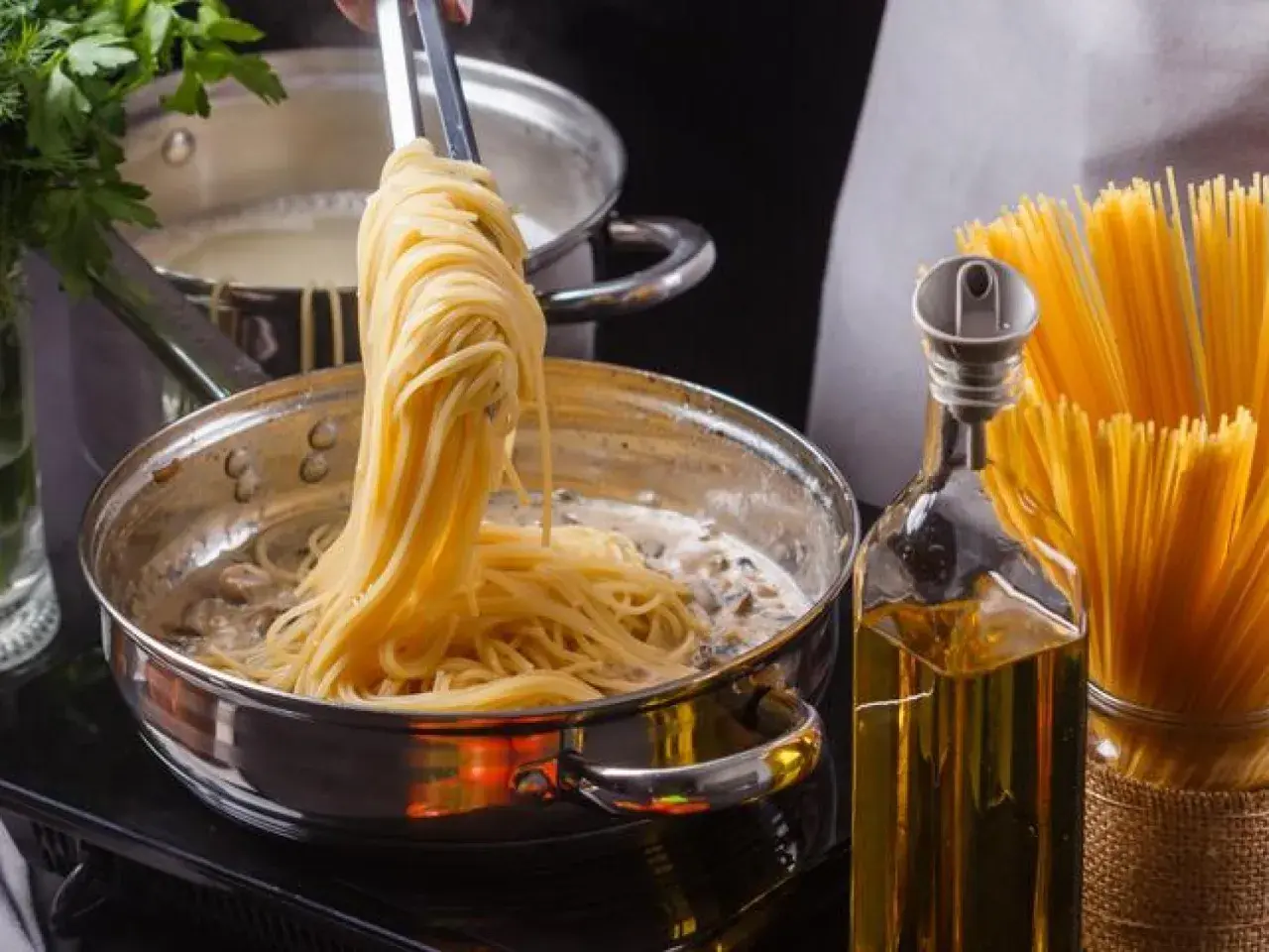 Unos espaguetis se añaden a una sartén con salsa cremosa, listos para convertirse en una deliciosa pasta al ajillo.