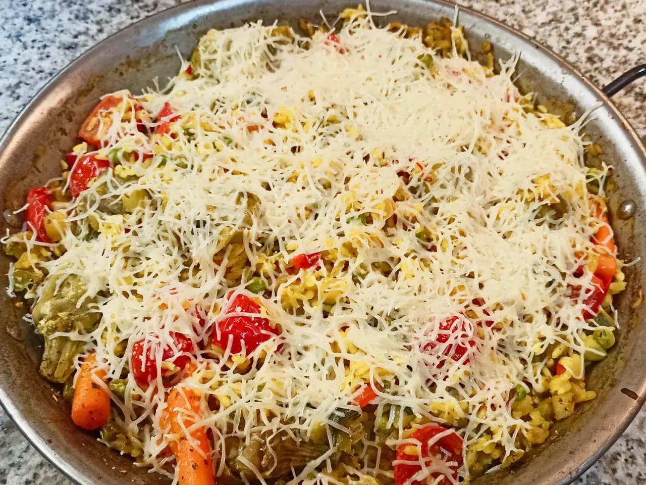 Arroz a la milanesa listo para hornear, con verduras y abundante queso rallado.