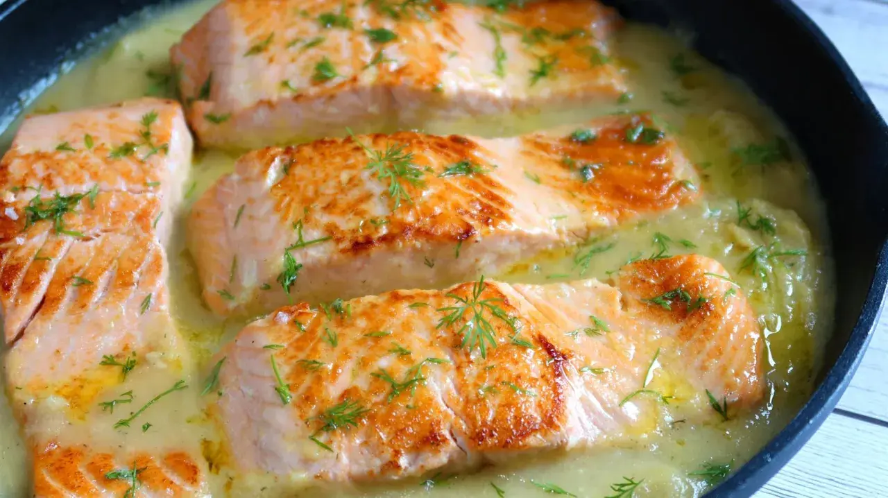 Filetes de salmón dorados en una cremosa salsa de eneldo, perfectos para tus recetas con salmón.