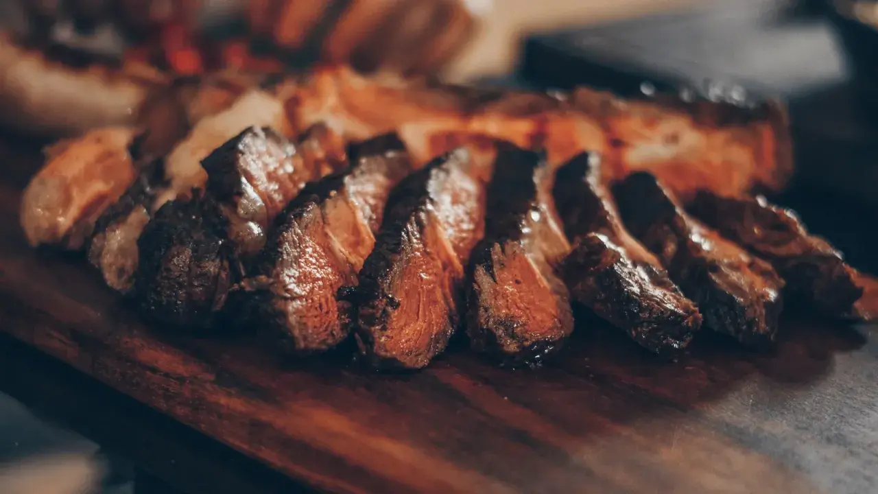 Filete de ternera jugoso y perfectamente cocinado, cortado en rodajas y servido en una tabla de madera.
