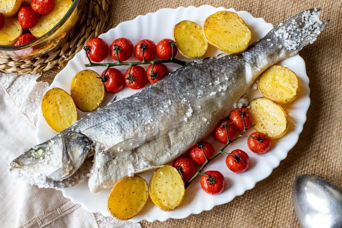 Lubina a la sal entera, horneada con patatas y tomates cherry. Un plato principal delicioso y saludable.