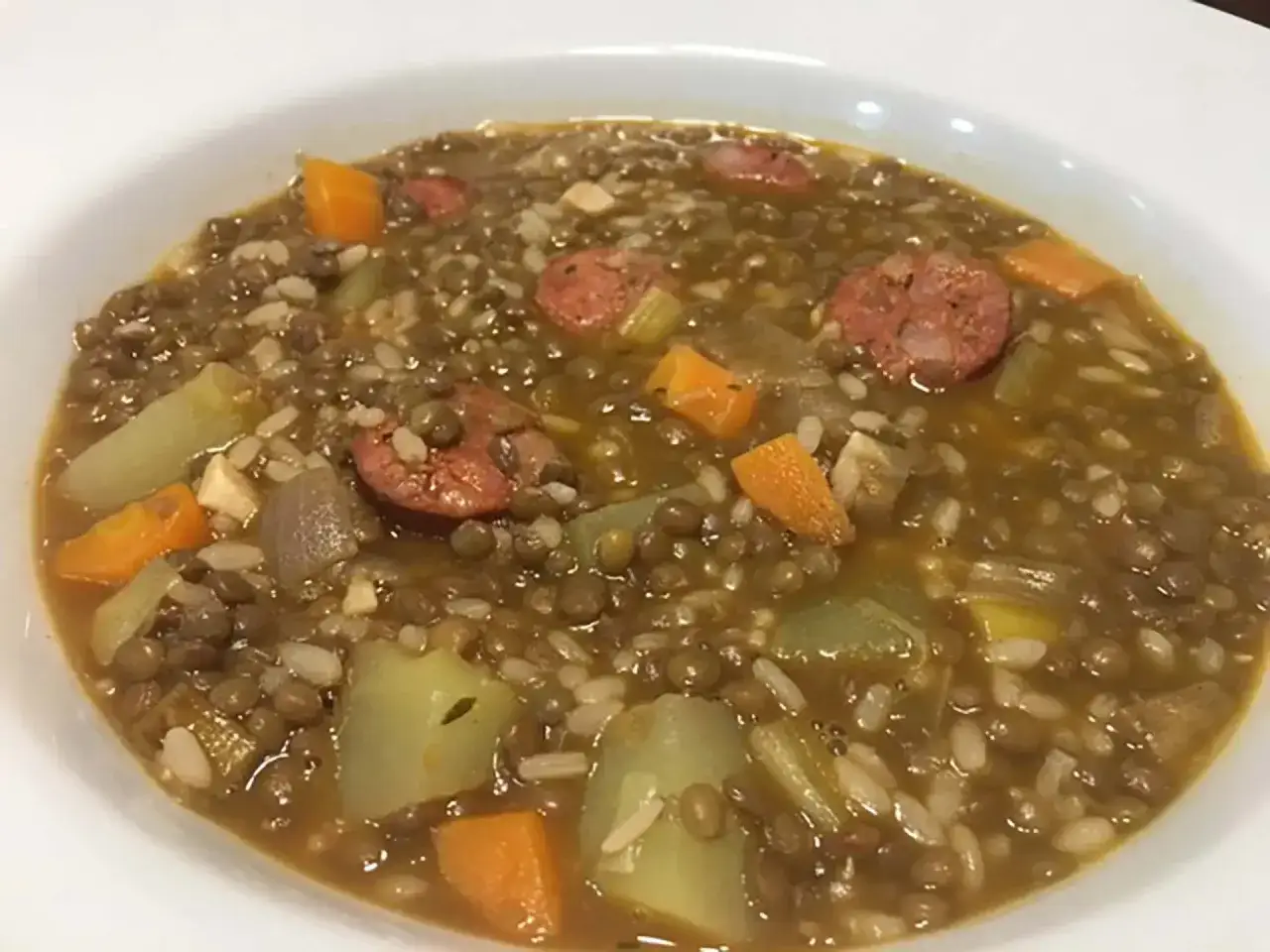 Un plato humeante de lentejas con arroz, trozos de zanahoria, patata y chorizo. Un guiso reconfortante y sabroso.