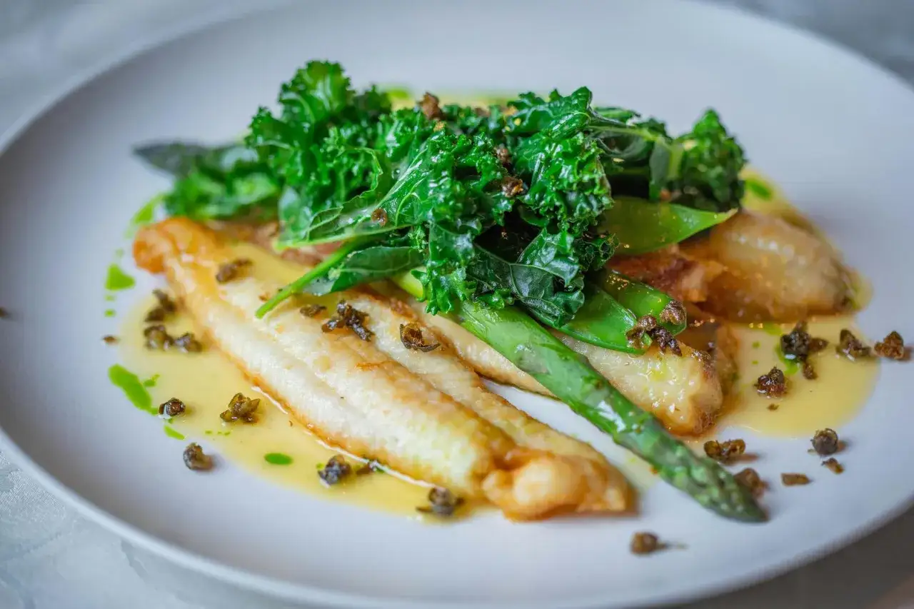 Filetes de pescado blanco con esp&aacute;rragos, kale y un toque de bacalao en salsa verde.