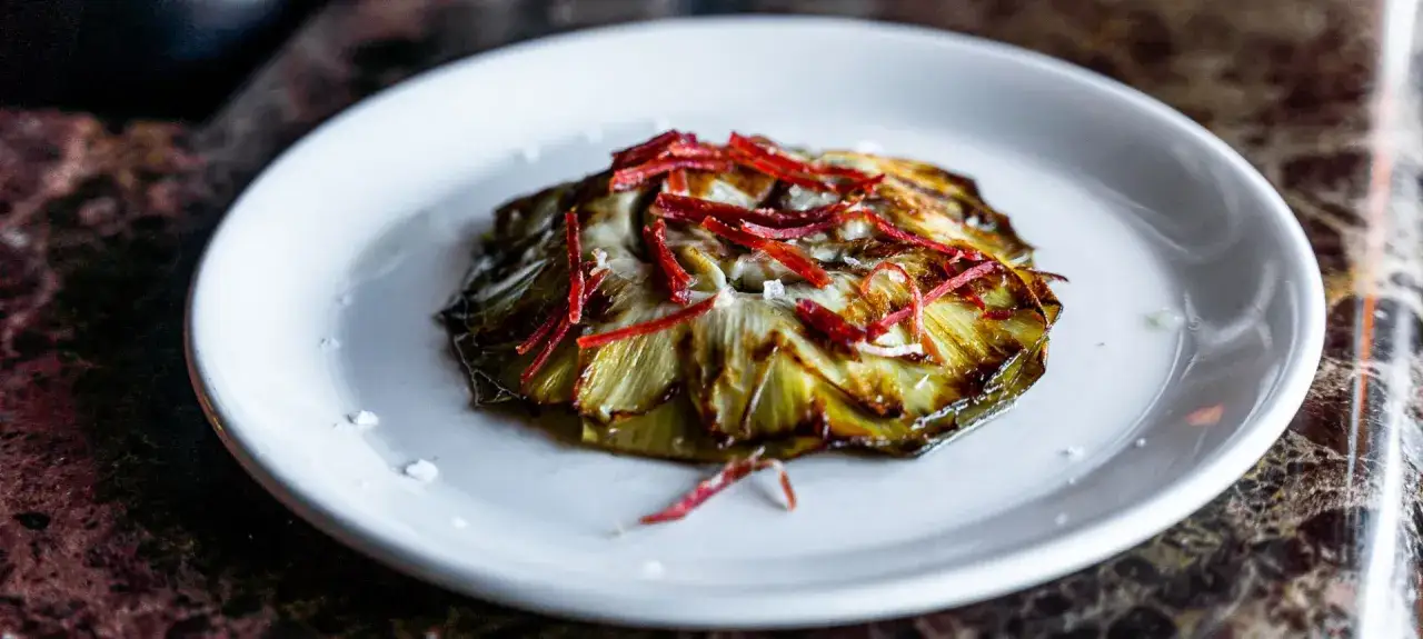 Deliciosas alcachofas confitadas, tiernas y doradas, coronadas con finas hebras rojas y sal marina. Un bocado exquisito.