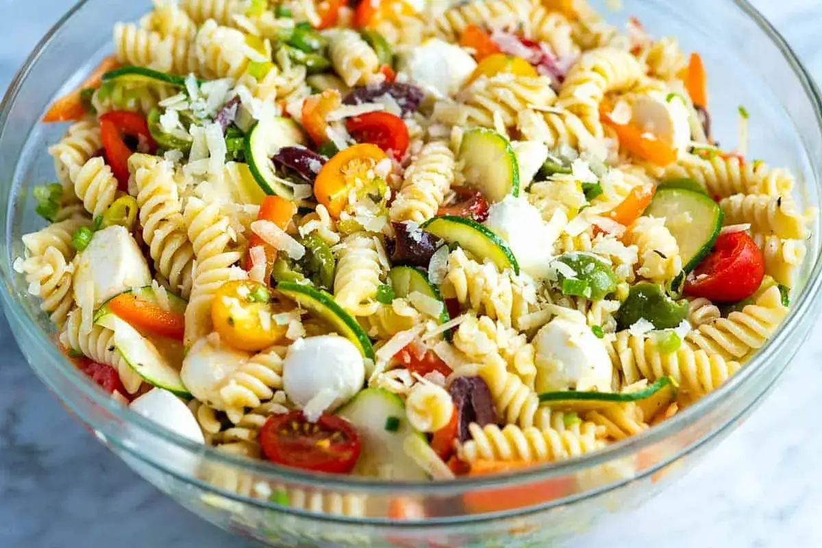 Ensalada de pasta con fusilli, tomates cherry, calabacín, aceitunas, pimientos y queso mozzarella. ¡Un festín de colores y sabores!