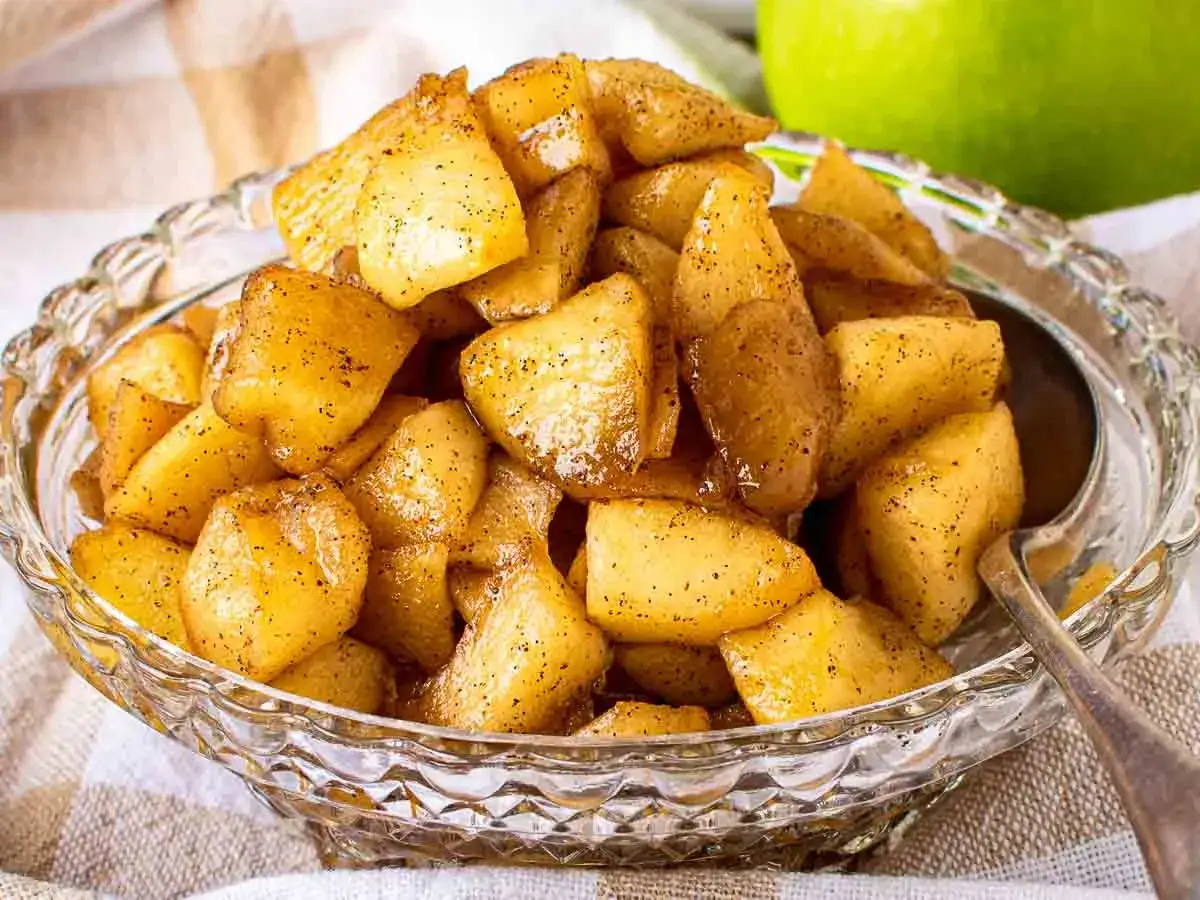 Compota de manzana casera, dorada y especiada, servida en un cuenco de cristal.