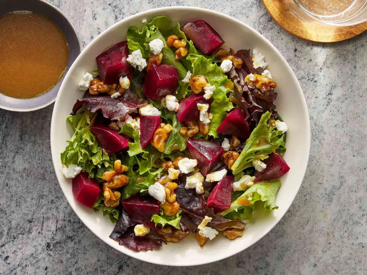 Ensalada de remolacha vibrante con queso de cabra desmenuzado y nueces crujientes sobre una cama de lechugas mixtas.