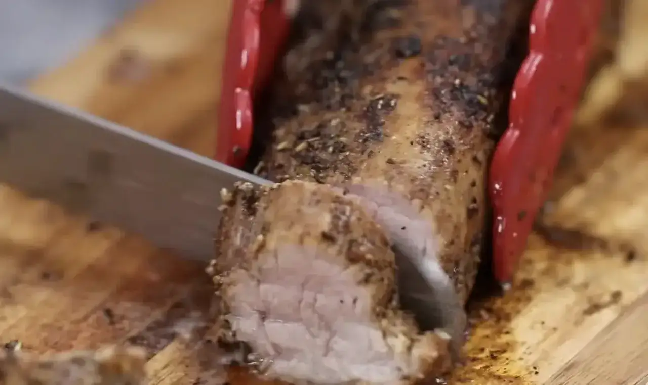 Un jugoso solomillo de cerdo al horno, recién cortado en una tabla de madera.