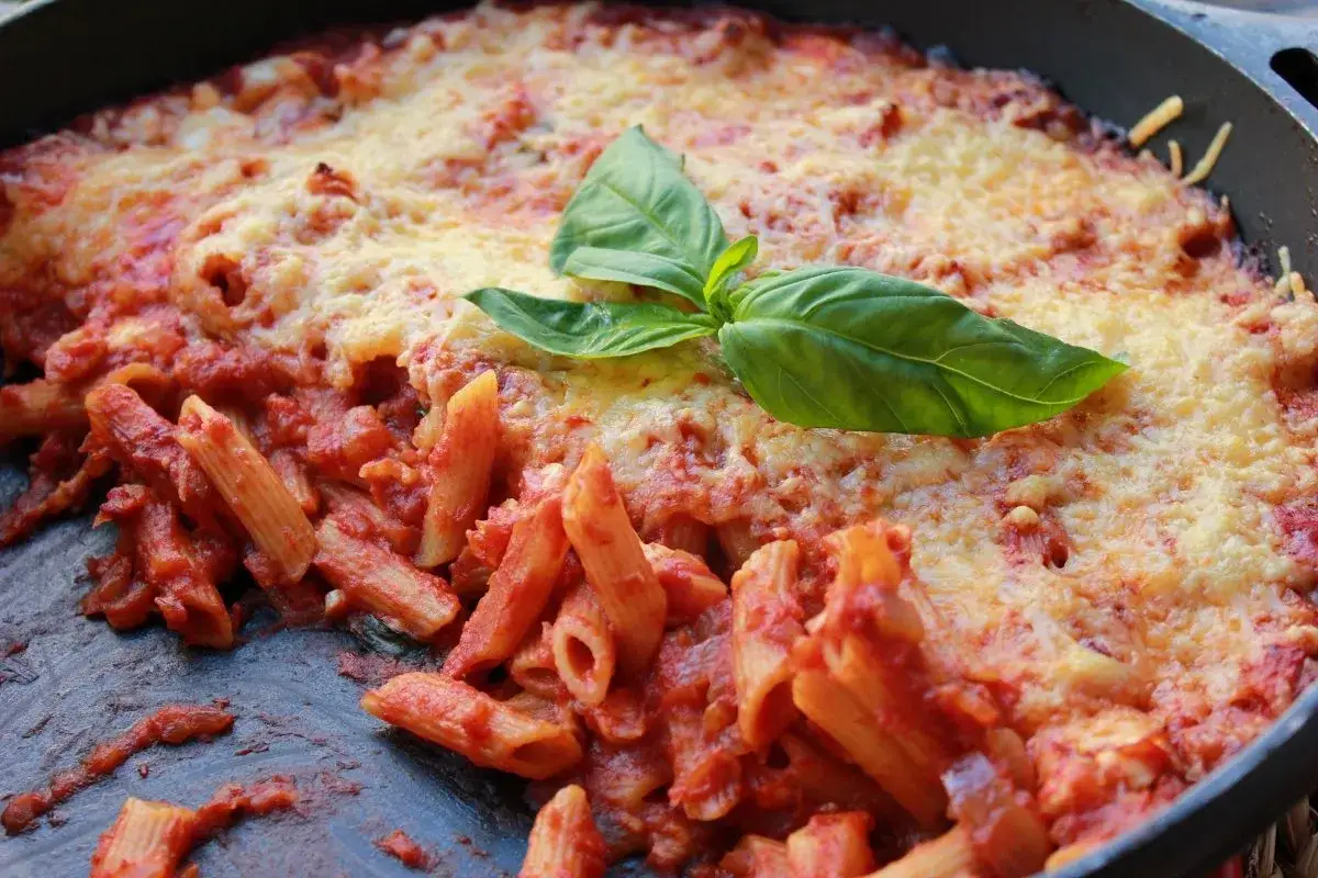 Macarrones con queso gratinados, con salsa de tomate y una hoja de albahaca fresca.