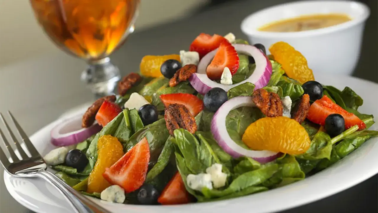 Ensalada de espinacas fresca con fresas, arándanos, naranja, cebolla morada y nueces.