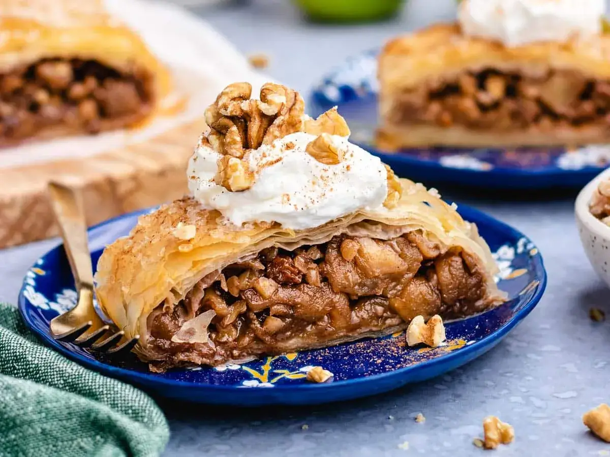 Delicioso strudel de manzana con nueces y crema batida, espolvoreado con canela.