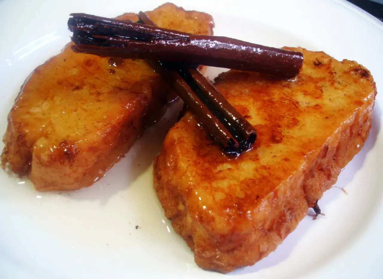Dos deliciosas torrijas doradas, empapadas en almíbar y coronadas con canela. ¡Una receta irresistible!