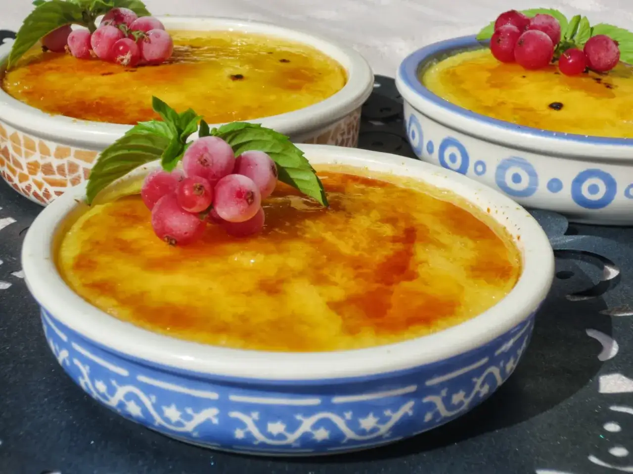 Deliciosa crema catalana hecha en Thermomix, con una capa crujiente de caramelo y decorada con grosellas rojas y menta.