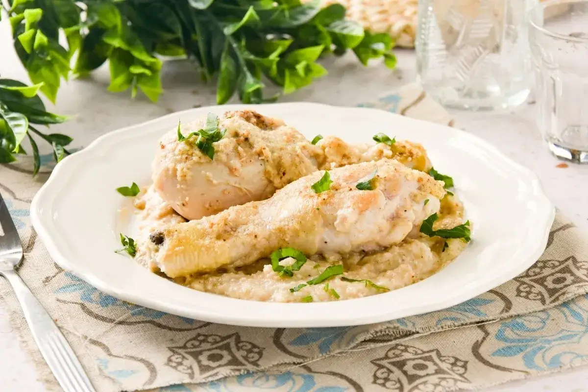 Pollo con almendras cremoso, servido en un plato blanco con perejil picado. Un plato delicioso y reconfortante.