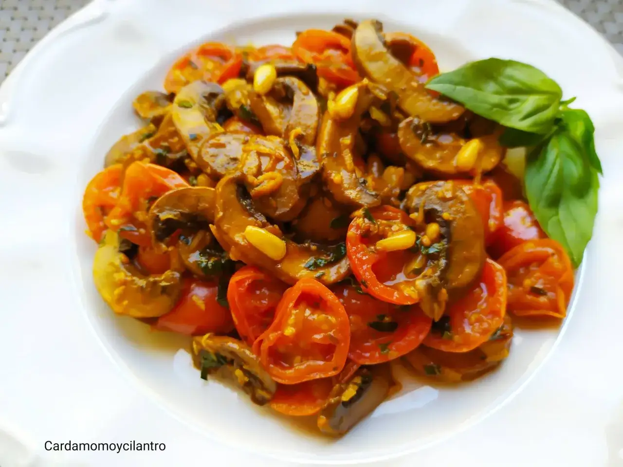 Plato de champiñones salteados con tomates cherry y albahaca. Una deliciosa opción para tus recetas con champiñones.