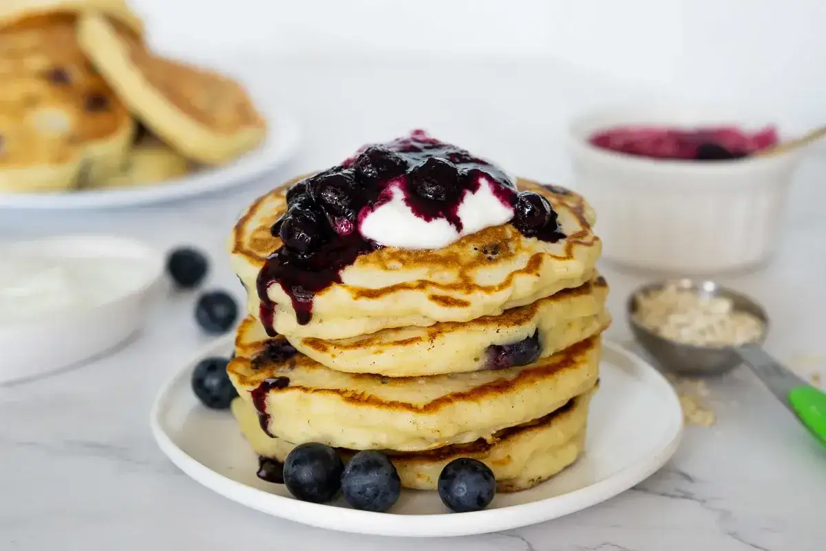 Deliciosas tortitas de avena con arándanos, cubiertas de yogur y mermelada de frutos rojos. ¡Un desayuno perfecto!
