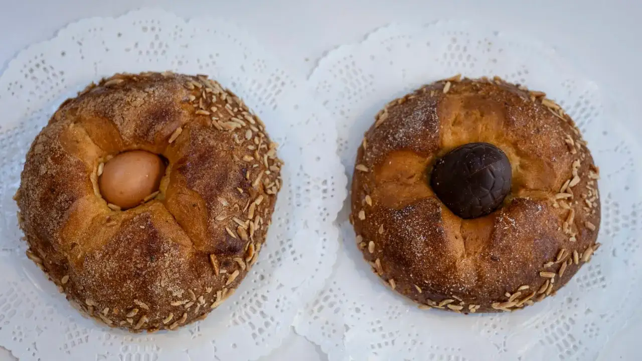 Dos monas de Pascua catalanas, una con huevo cocido y otra con un huevo de chocolate, decoradas con almendras y azúcar.