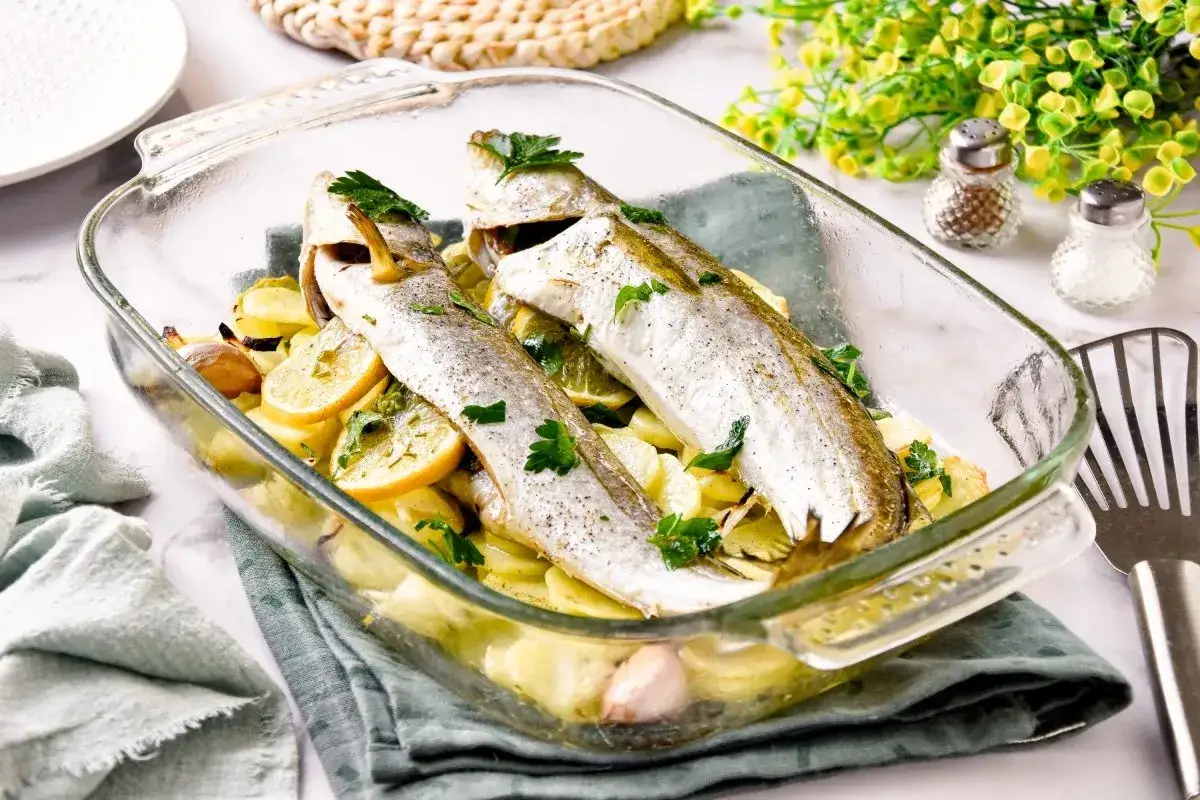 Pescadilla al horno con patatas, lim&oacute;n y ajo, reci&eacute;n salida del horno. Un plato sencillo y delicioso.