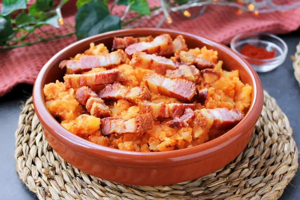 Un cuenco de barro con patatas revolconas, cubiertas de trozos crujientes de panceta. Un plato tradicional español.