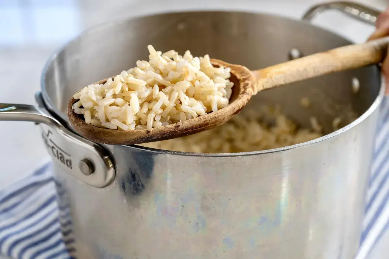 Cuchara de madera con arroz integral cocido, lista para servir. Aprende como hacer arroz integral perfecto.